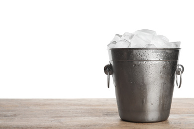 Metal bucket with ice cubes on wooden table against white background