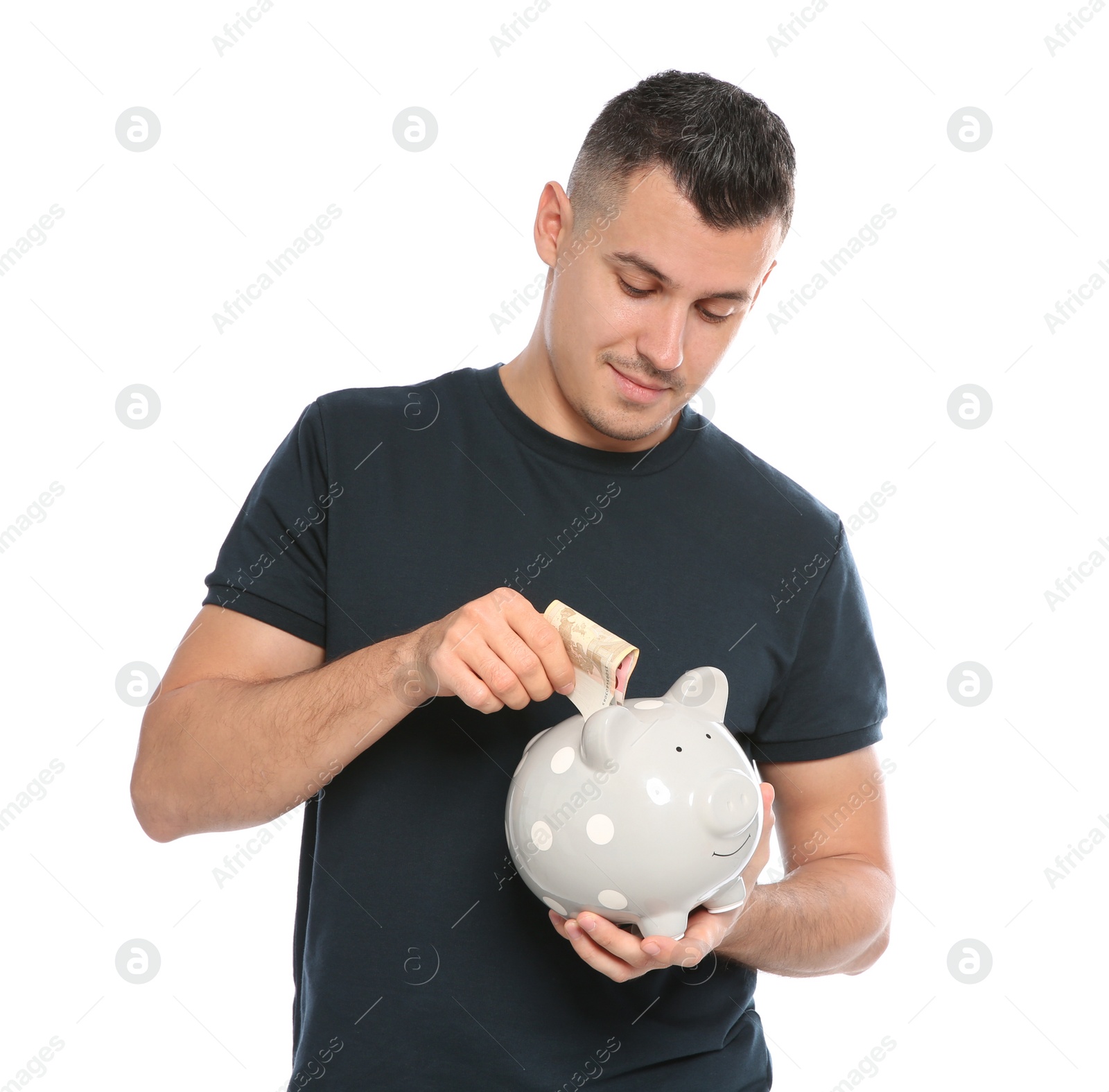 Photo of Portrait of man putting money into piggy bank on white background