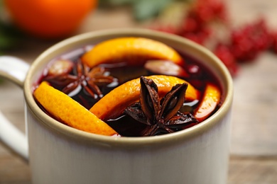 Cup with tasty mulled wine on table, closeup