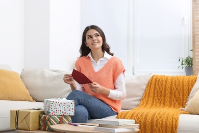 Young woman with greeting card in living room
