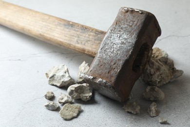 One sledgehammer and pieces of broken stones on grey textured background, closeup