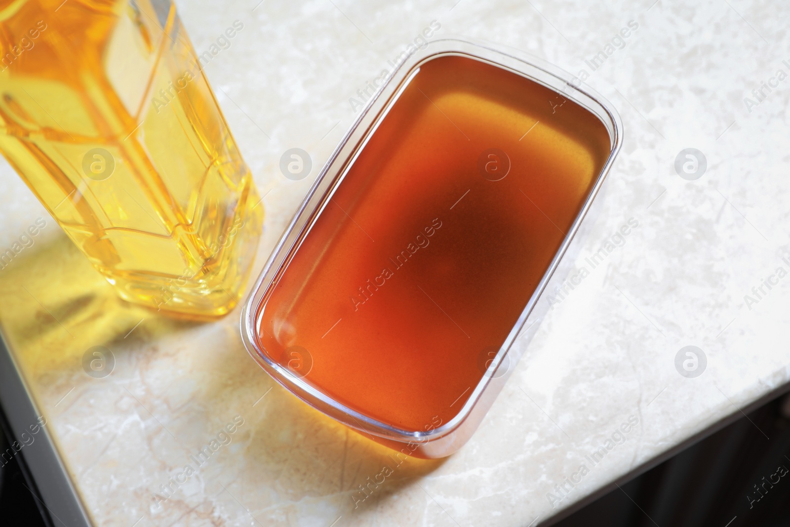 Photo of New and used cooking oil on beige marble table, above view