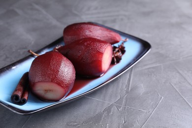 Tasty red wine poached pears and spices on grey table, closeup. Space for text