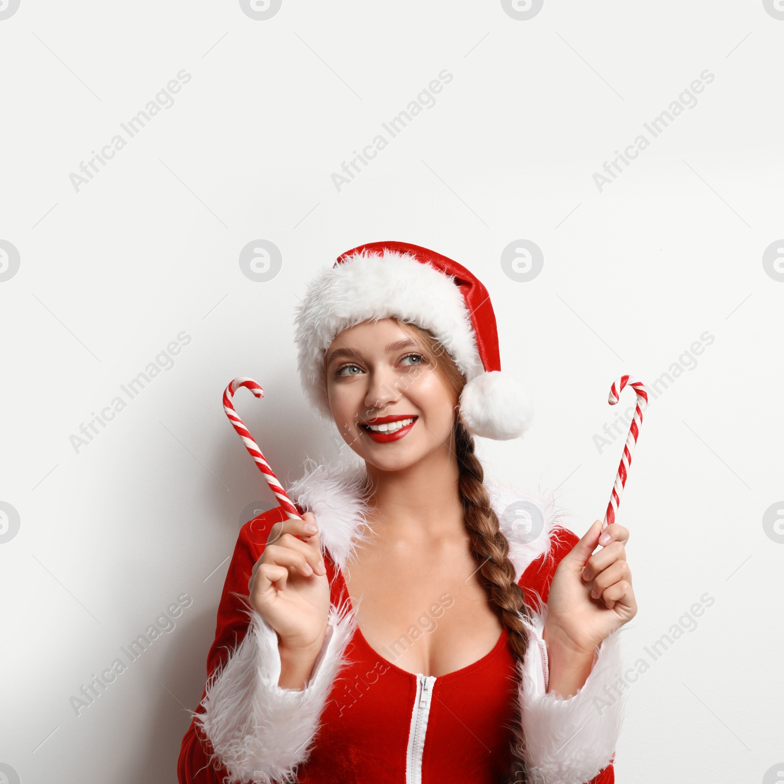 Photo of Beautiful Santa girl with candy canes on light background. Christmas eve