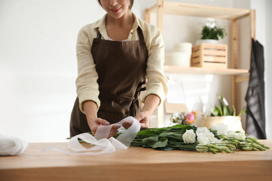 Florist making beautiful bouquet at table in workshop, closeup