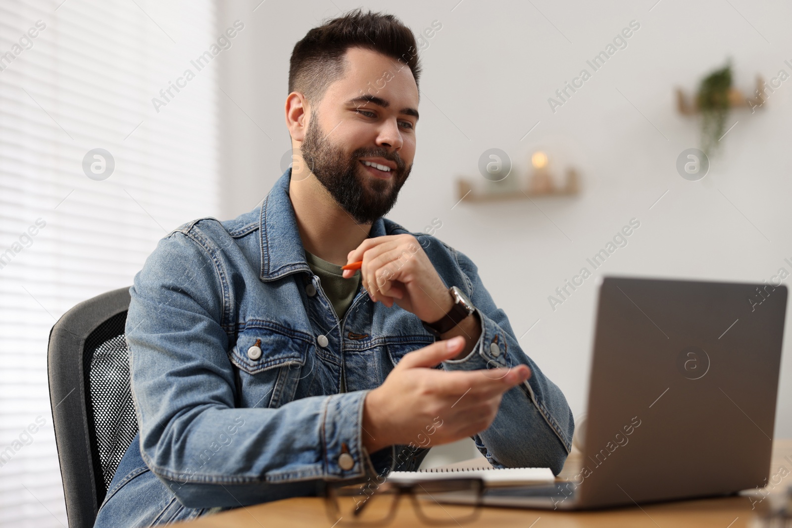 Photo of Young man using video chat during webinar at table in room