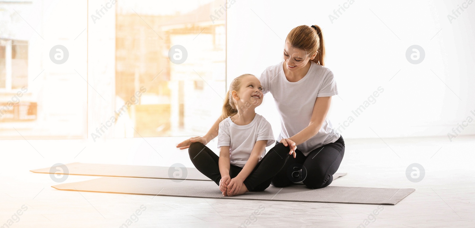 Image of Mother and daughter doing yoga together at home. Banner design