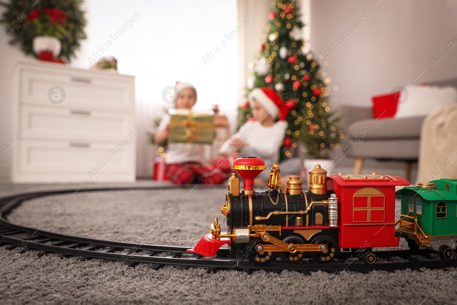 Photo of Children playing with colorful toy in room decorated for Christmas, focus on train