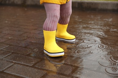 Photo of Girl walking in puddle outdoors on rainy weather, closeup