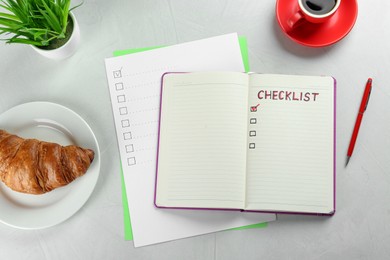 Notebook with inscription Checklist, cup of coffee and croissant on white table, flat lay
