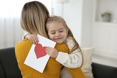 Photo of Little daughter congratulating her mom with greeting card at home, space for text. Happy Mother's Day