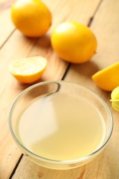 Photo of Freshly squeezed lemon juice in bowl on wooden table