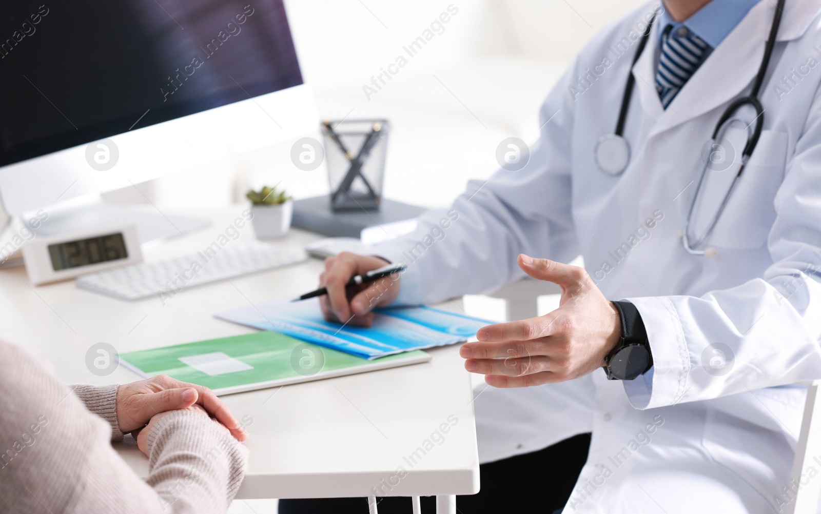 Photo of Doctor consulting patient at desk in clinic, closeup