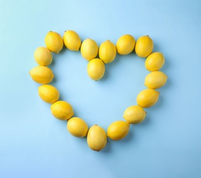 Heart made of fresh lemon fruits on light blue background, flat lay. Space for text