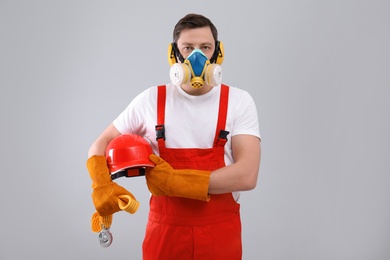 Photo of Male industrial worker in uniform on light background. Safety equipment