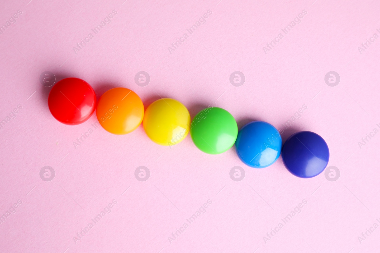 Photo of Bright magnets on pink background, flat lay. Rainbow colors