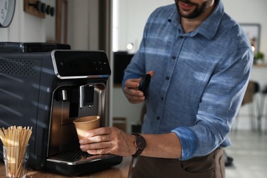 Man preparing fresh aromatic coffee with modern machine in office, closeup