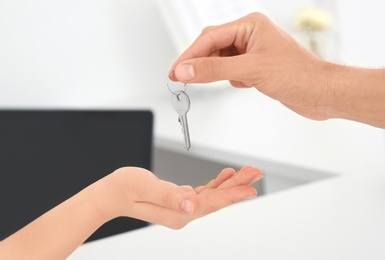 Young man giving key to receptionist in hotel, closeup