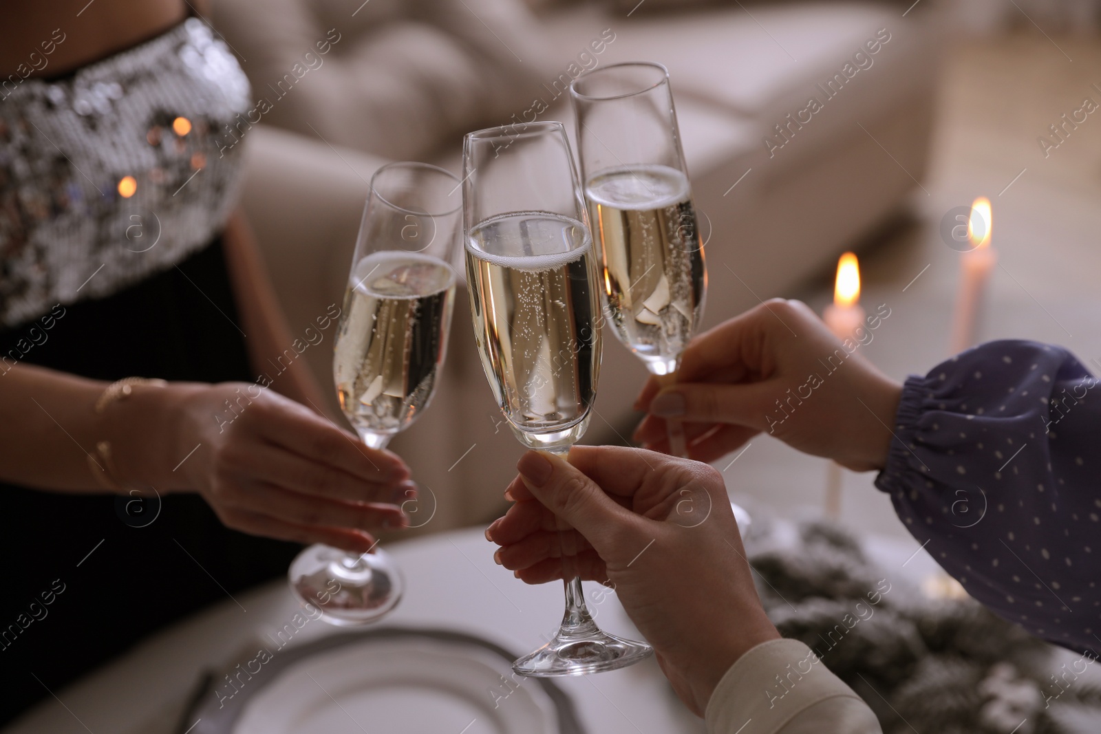 Photo of People clinking glasses with champagne at home, closeup