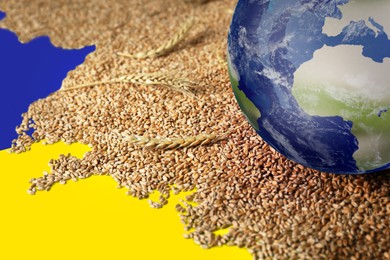 Image of Global food crisis concept. Wheat grains and globe of Earth on table in colors of Ukrainian flag