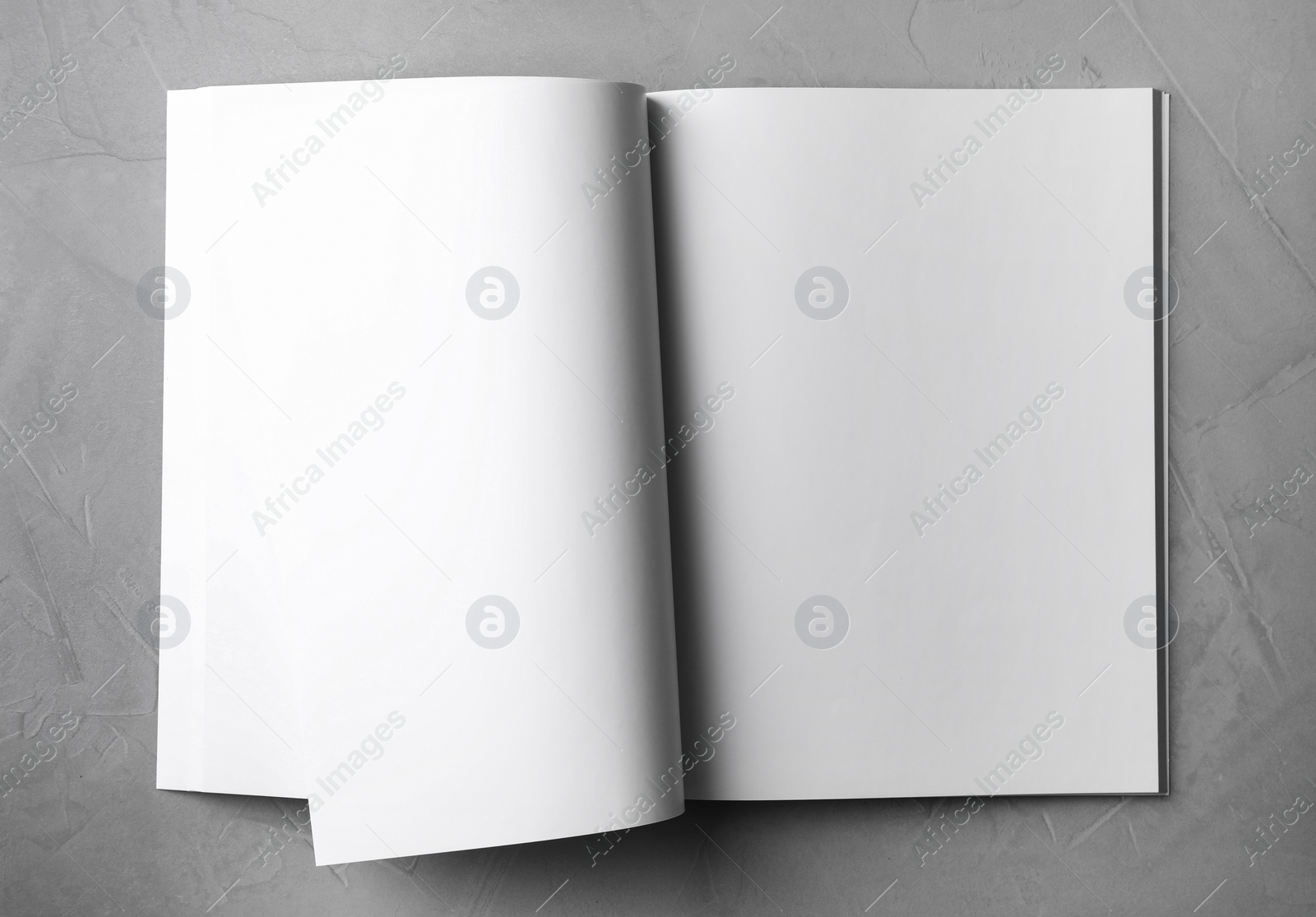 Photo of Blank open book on light grey stone background, top view. Mock up for design