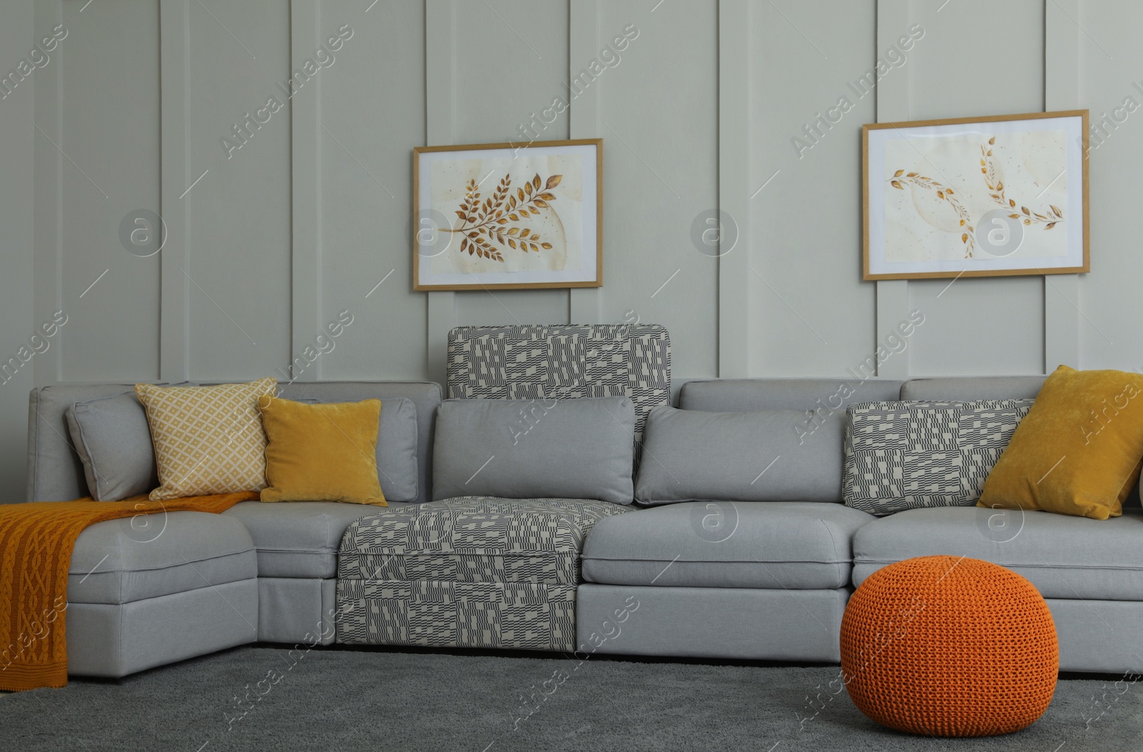 Photo of Comfortable large sofa with cushions and knitted blanket in living room