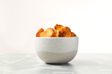 Photo of Bowl of sweet potato chips on table against white background