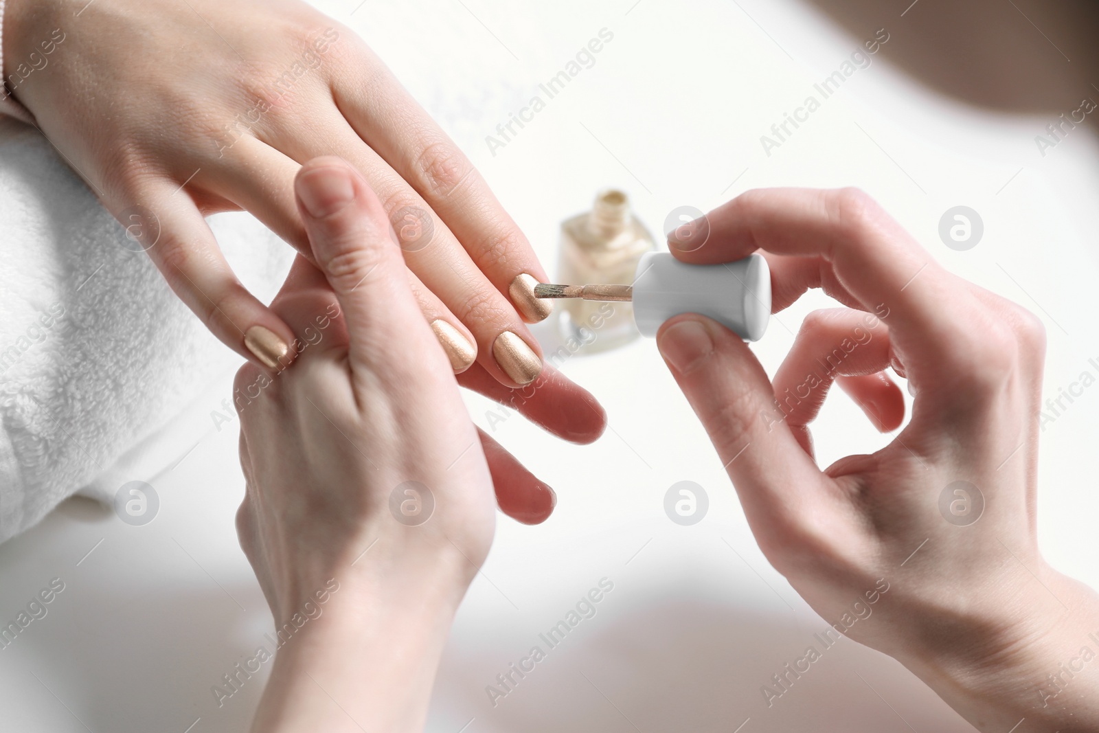 Photo of Manicurist painting client's nails with polish in salon, closeup