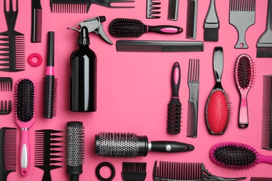Photo of Frame of modern hair combs and brushes on pink background, flat lay. Space for text