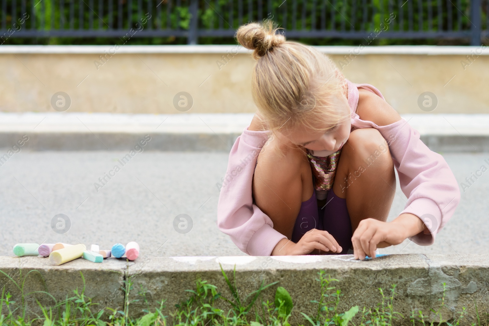 Photo of Little child drawing with chalk on curb outdoors, space for text