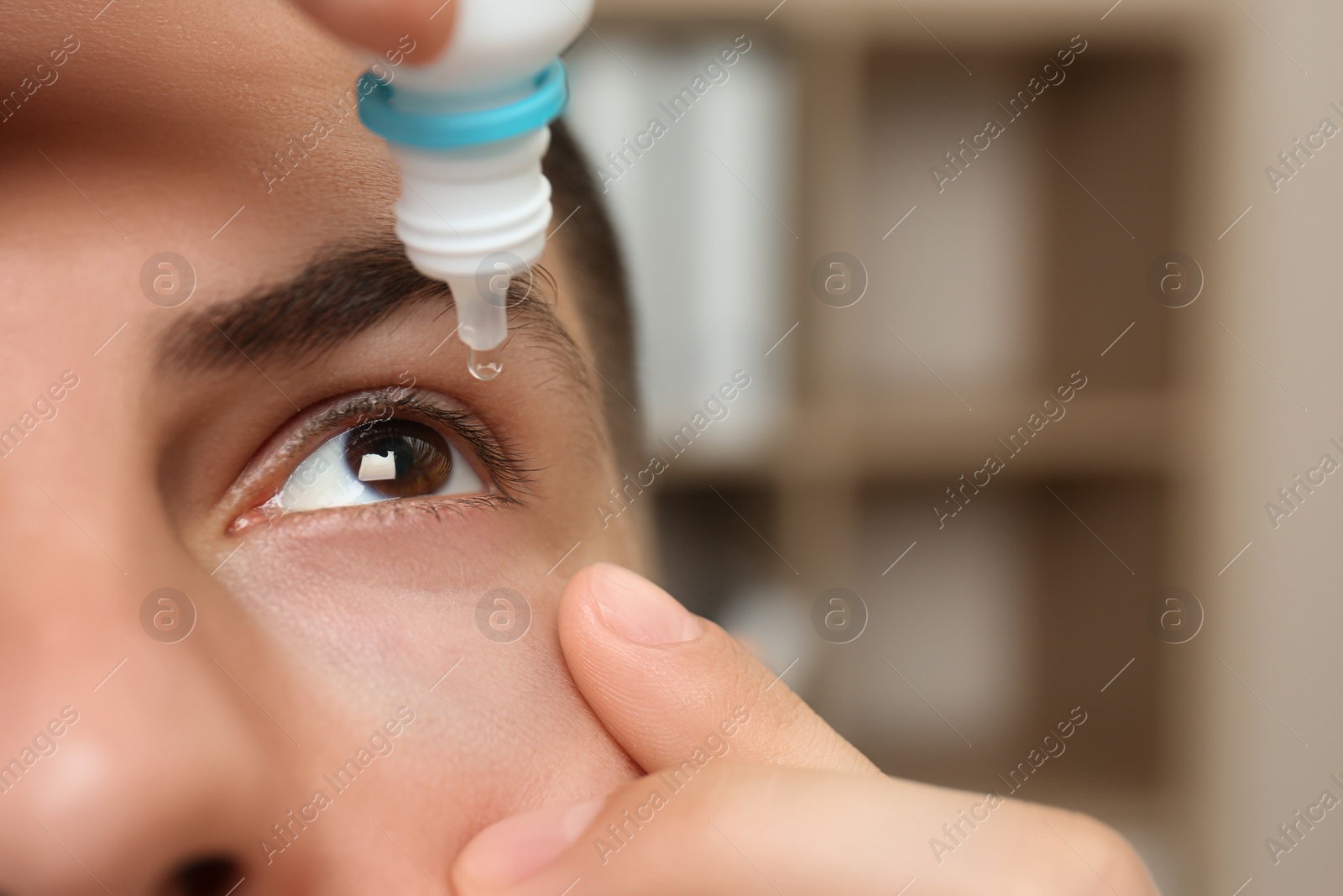 Photo of Man using eye drops on blurred background, closeup