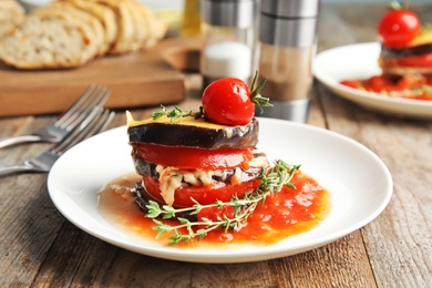 Baked eggplant with tomatoes, cheese and thyme on wooden table