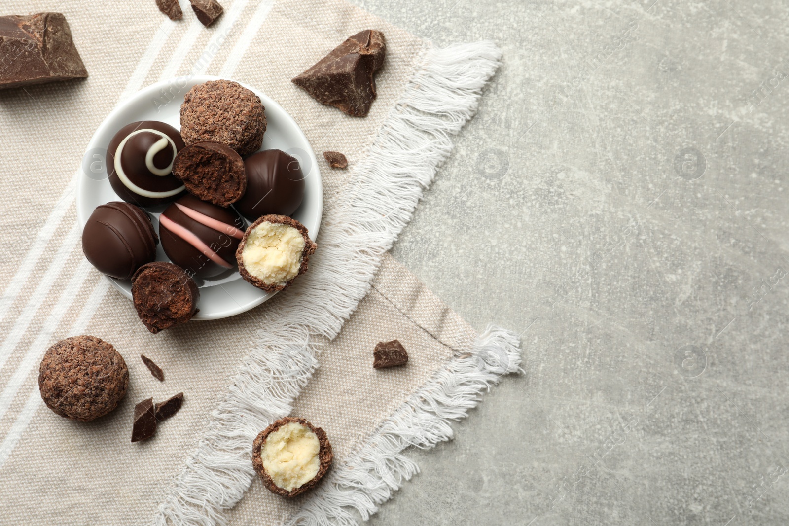 Photo of Many different delicious chocolate truffles on light table, top view. Space for text