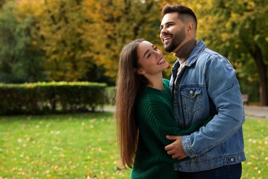 Photo of Romantic young couple spending time together in autumn park, space for text