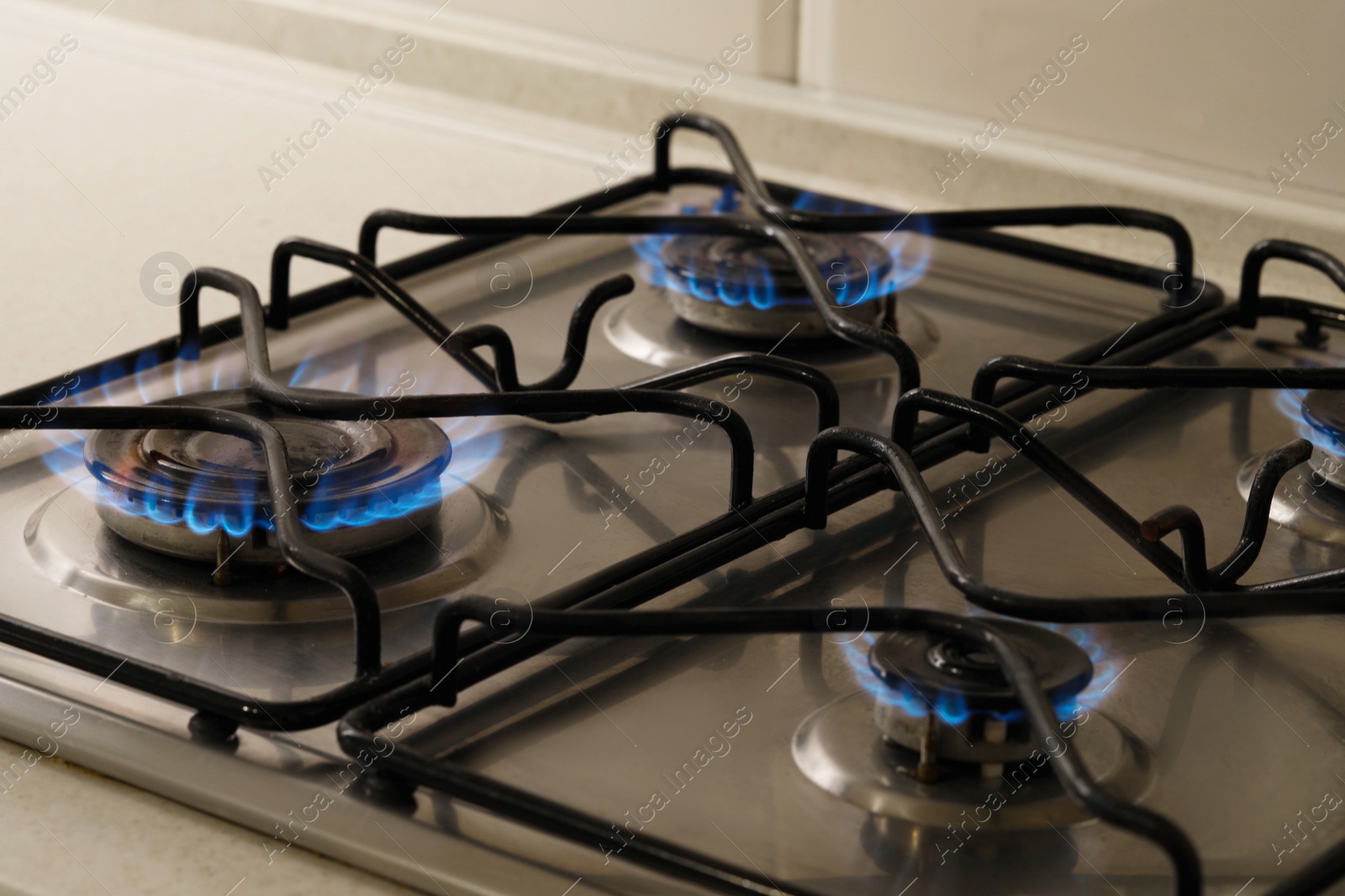 Photo of Gas cooktop with burning blue flames, closeup