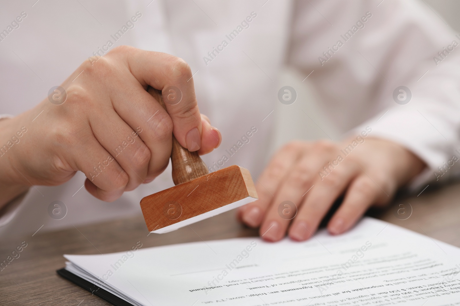 Photo of Man stamping document at wooden table, closeup