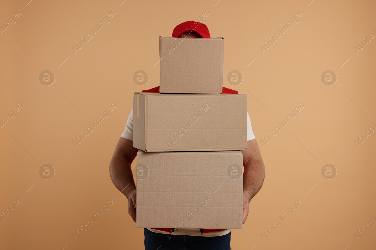 Photo of Courier with stack of parcels on light brown background