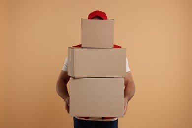 Courier with stack of parcels on light brown background