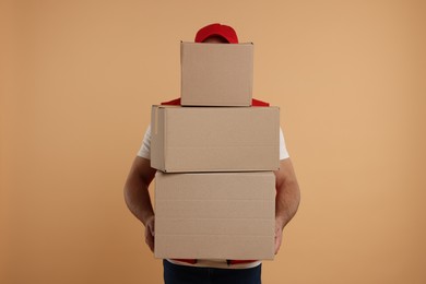 Photo of Courier with stack of parcels on light brown background