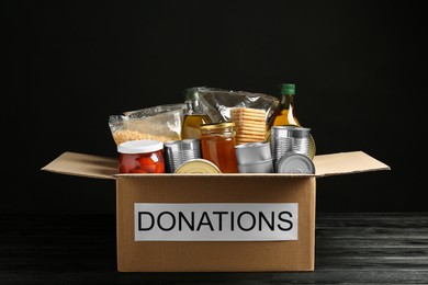 Photo of Donation box with food on black wooden table