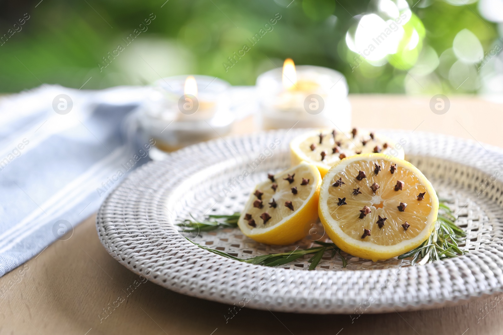 Photo of Lemons with cloves and fresh rosemary on wooden table outdoors, closeup. Natural homemade repellent