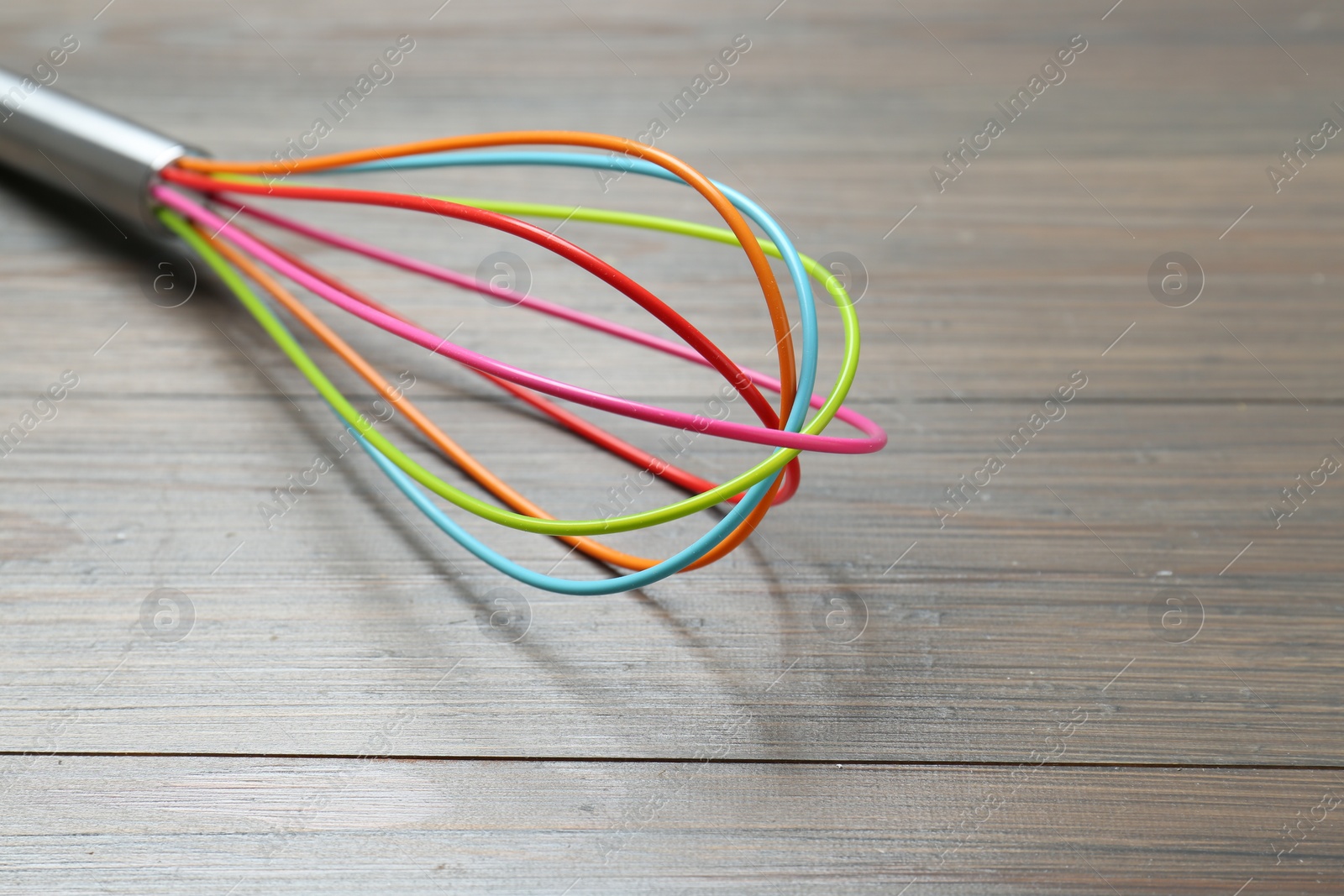 Photo of One whisk on wooden table, closeup. Space for text
