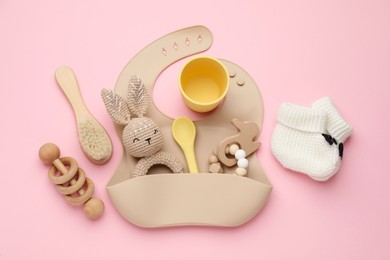 Flat lay composition with baby accessories and bib on pink background