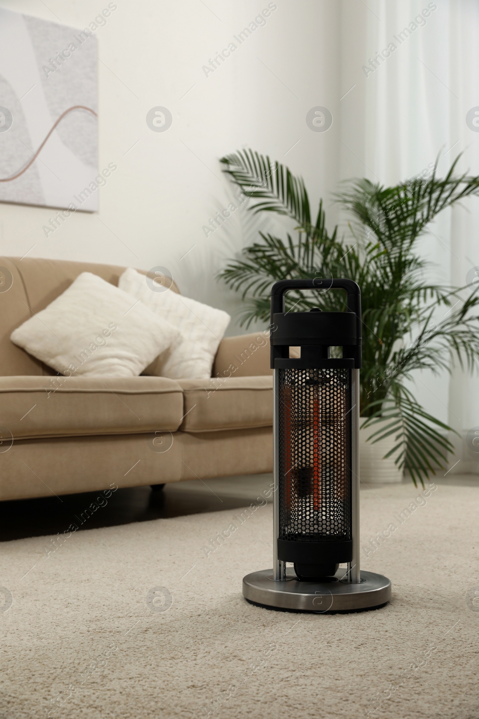 Photo of Modern electric halogen heater on floor in living room interior