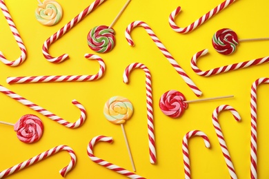 Photo of Flat lay composition with candy canes and lollipops on yellow background