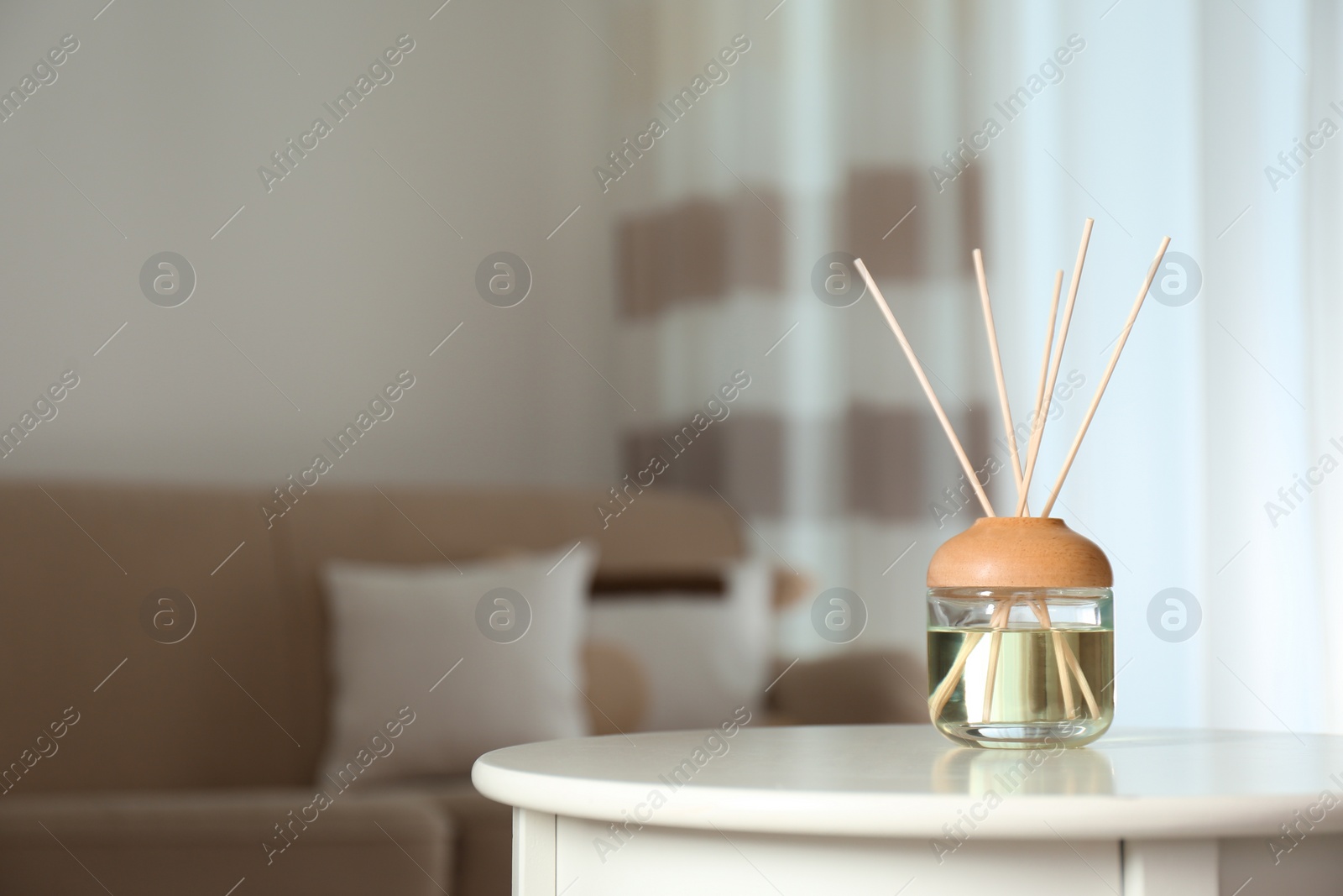 Photo of Aromatic reed air freshener on table indoors. Space for text