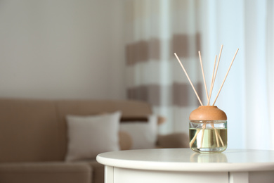 Photo of Aromatic reed air freshener on table indoors. Space for text