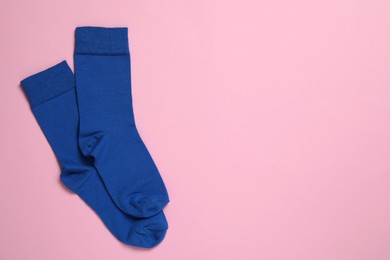 Photo of Pair of new blue socks on pink background, flat lay. Space for text