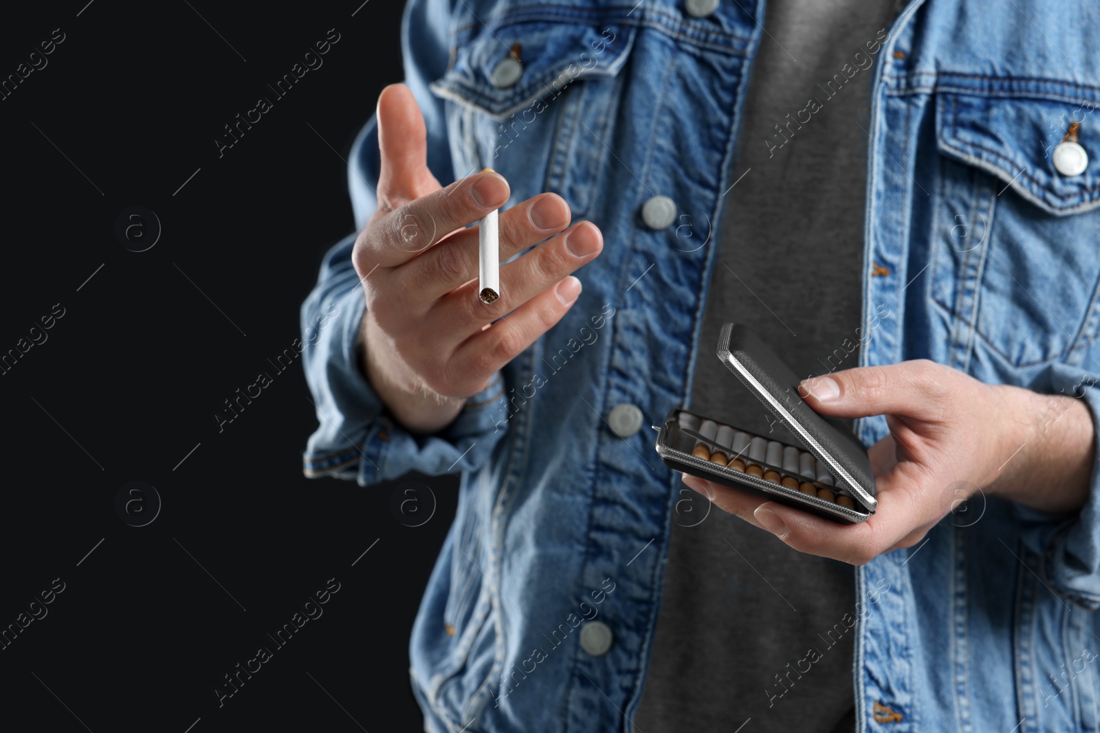 Photo of Man taking cigarette from case on black background, closeup. Space for text