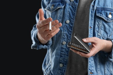 Man taking cigarette from case on black background, closeup. Space for text